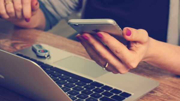 women holding cell phone, using computer & flash drive