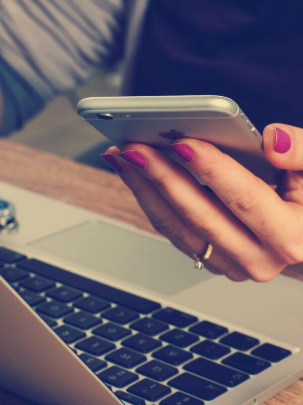 women holding cell phone, using computer & flash drive