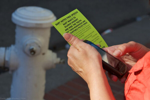Person holding cell phone and flyer