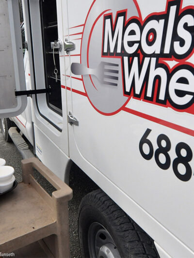 A Meals on Wheels driver loading food into a truck