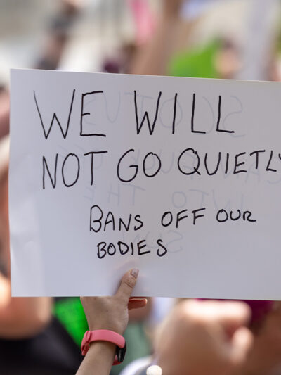 Abortion Rights protestor holds a sign reading "WE WILL NOT GOT QUIETLY, BANS OFF OUR BODIES"