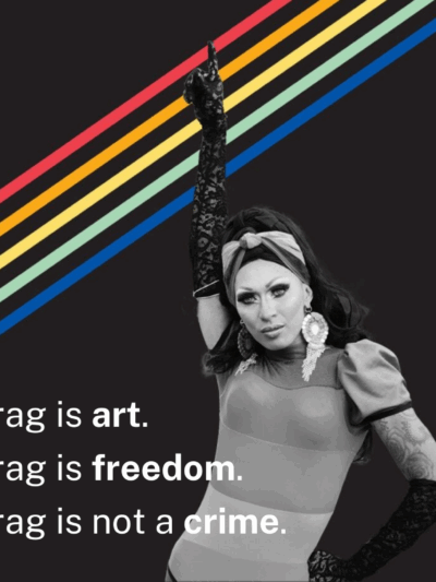 A black-and-white photo of a drag queen pointing skyward over a black background with rainbow stripes. The text reads: "Drag is art. Drag is freedom. Drag is not a crime."