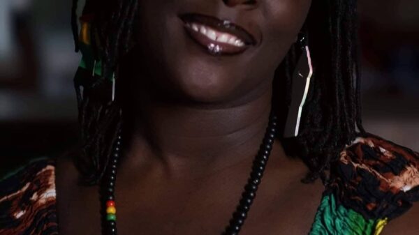 A photo of Brittany Martin. She is wearing a green, red, yellow, and black top and is smiling at the camera.