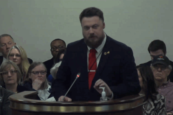 ACLU-SC Advocacy Strategist Matthew Butler addresses a subcommittee. He is wearing a suit and red tie and is standing behind a lectern with a microphone.