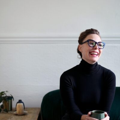 Photo of author Elana K. Arnold smiling in a black shirt holding a mug