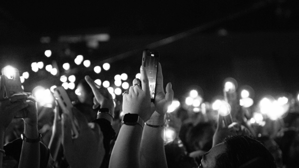 A crowd holds up smartphones with their flashlights on