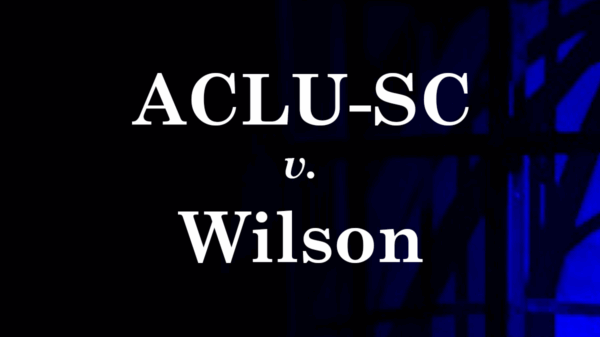 "ACLU-SC v. Wilson." White text on a dark background with shadows of a cage cast by blue and red light.