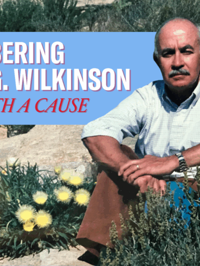"Remembering Harry G. Wilkinson, Rebel with a Cause." Photo of Harry, a man in a button-up shirt with the sleeves rolled up, seated on some rocks with an outcropping of flowering scrub plants.