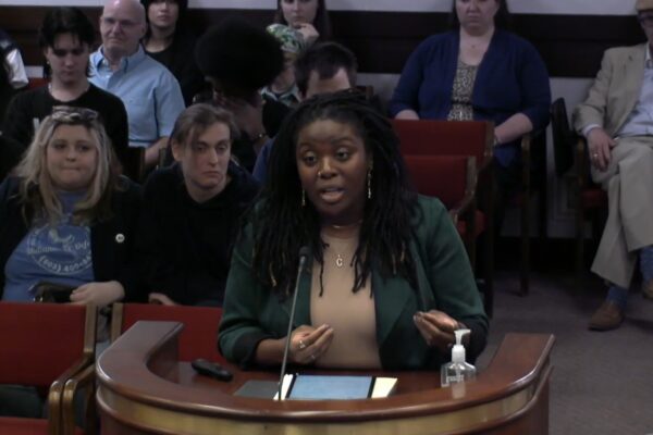 ACLU-SC Advocacy Director Courtney Thomas addresses lawmakers from behind a podium in a Statehouse subcommittee hearing.