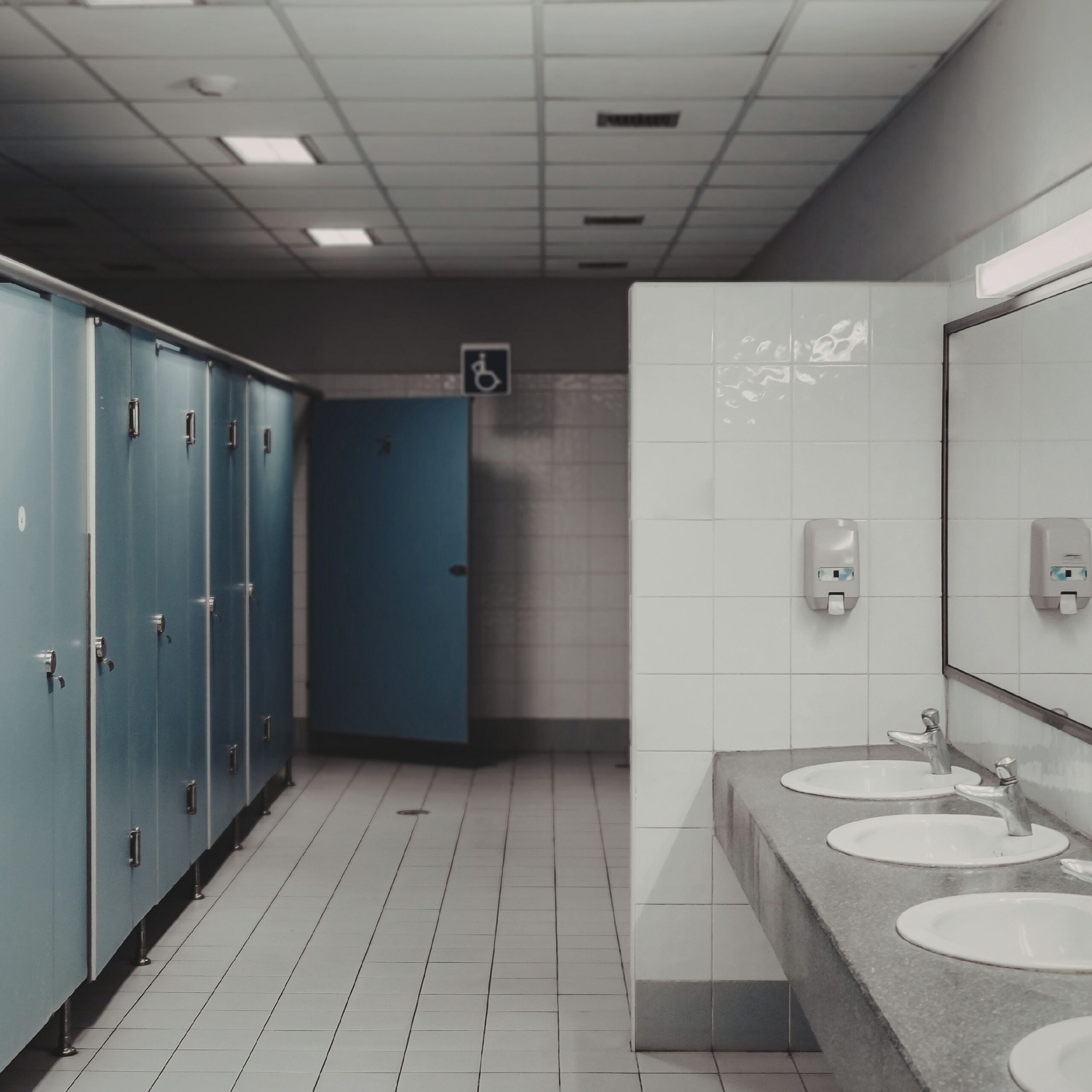 Photo of a public restroom with tile floor and stalls