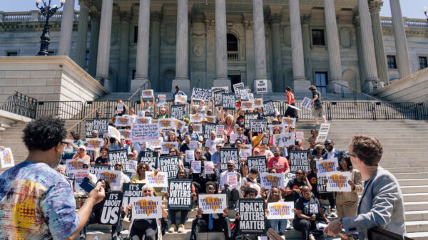 A crowd of protesters on the Statehouse steps. Signs say "This is what democracy looks like" and "Black voters matter."