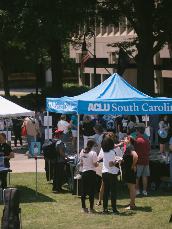 Protesters gather on the Statehouse lawn near an ACLU of South Carolina pop-up tent