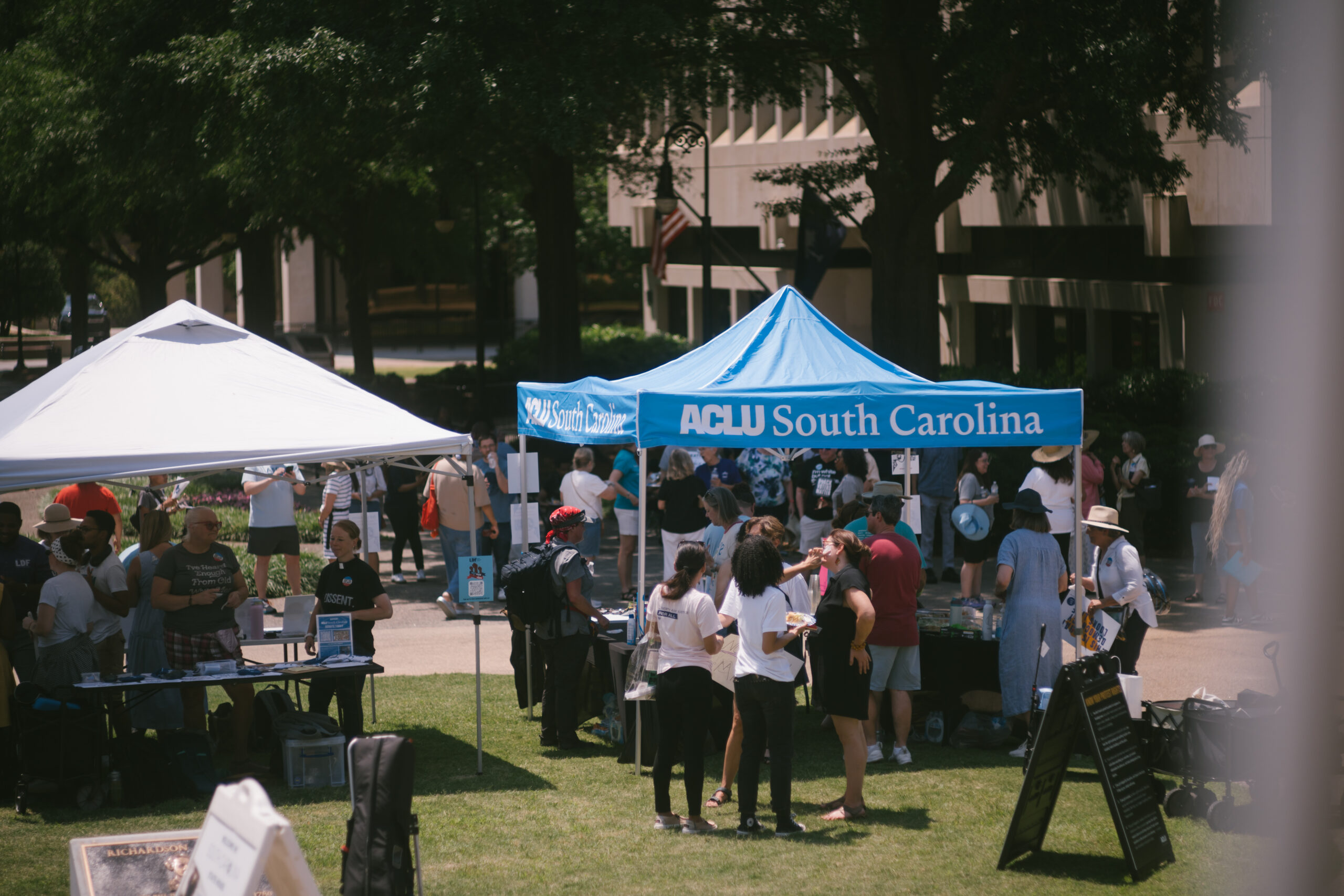 Protesters gather on the Statehouse lawn near an ACLU of South Carolina pop-up tent