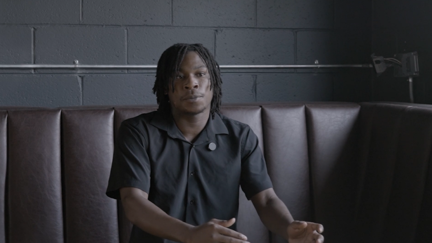image of a Black male with a black polo shirt