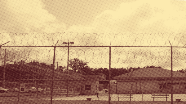 Sepia-toned photo of a juvenile justice facility behind a razor wire fence