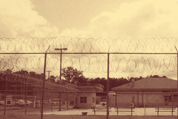 Sepia-toned photo of a juvenile justice facility behind a razor wire fence