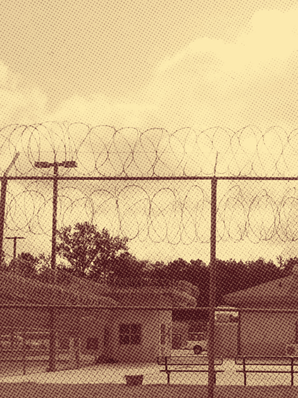 Sepia-toned photo of a juvenile justice facility behind a razor wire fence
