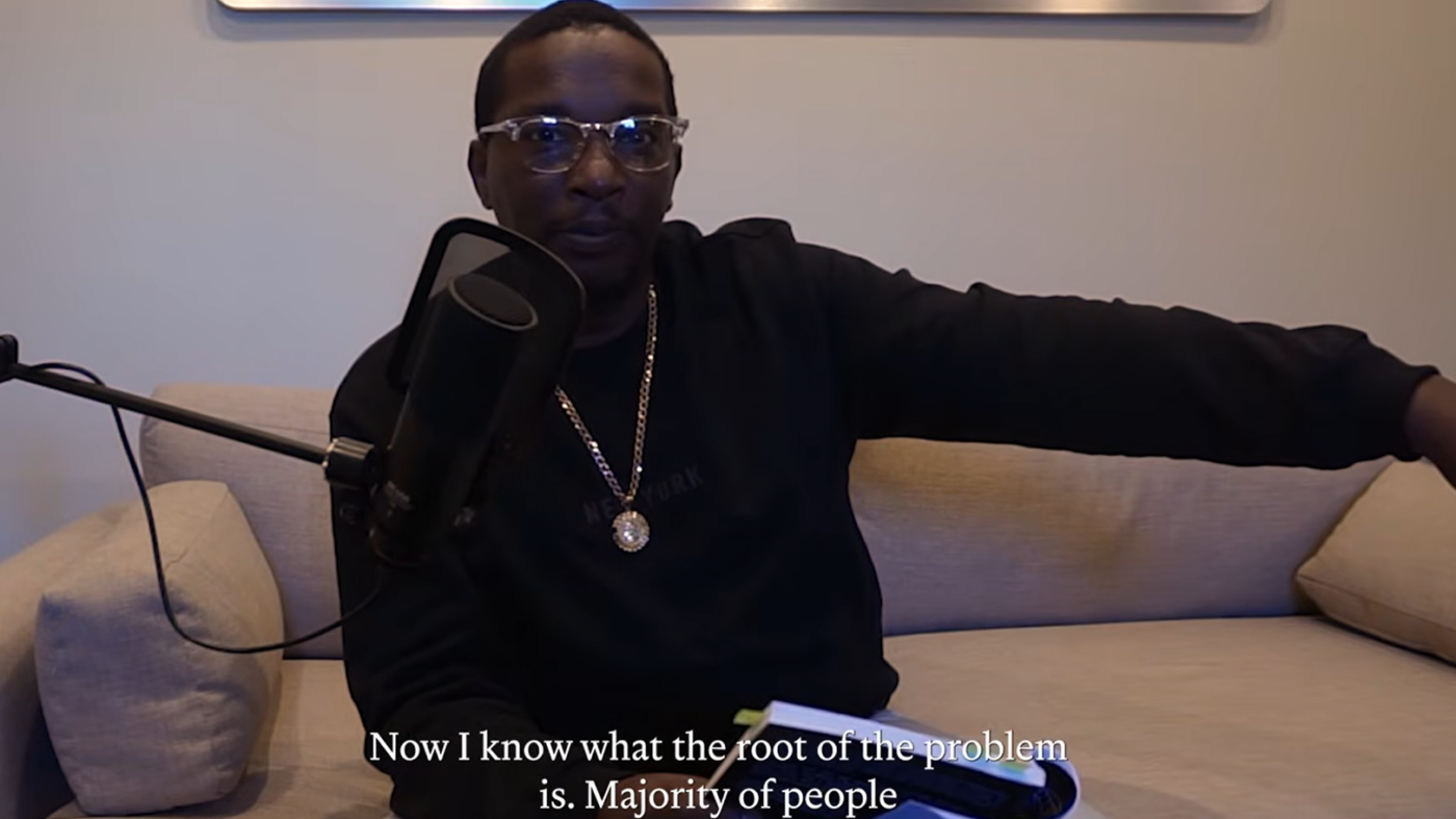 Video still of Alonzo Canzater, a Black man wearing a black sweater, seated on a couch speaking.
