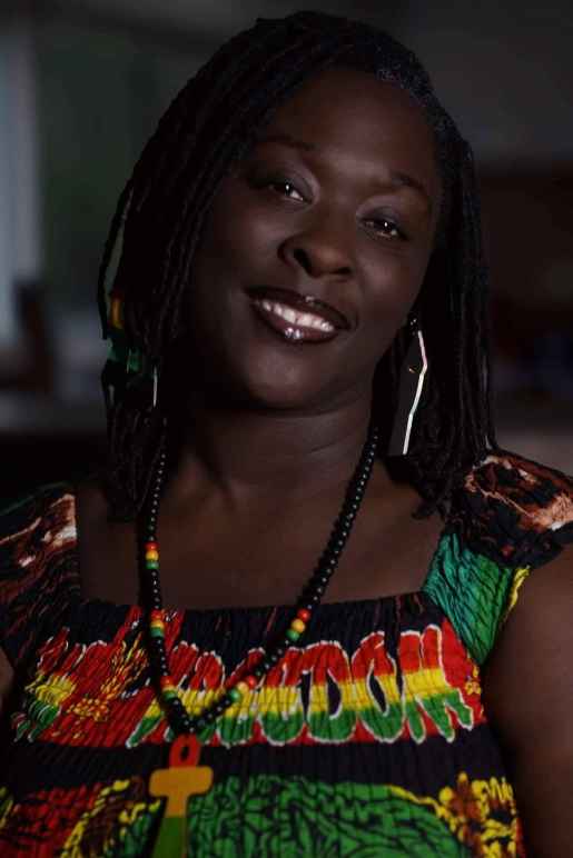 A photo of Brittany Martin. She is wearing a green, red, yellow, and black top and is smiling at the camera.