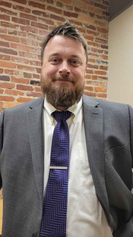 A photo of Matthew Butler in a gray sport coat with a blue tie