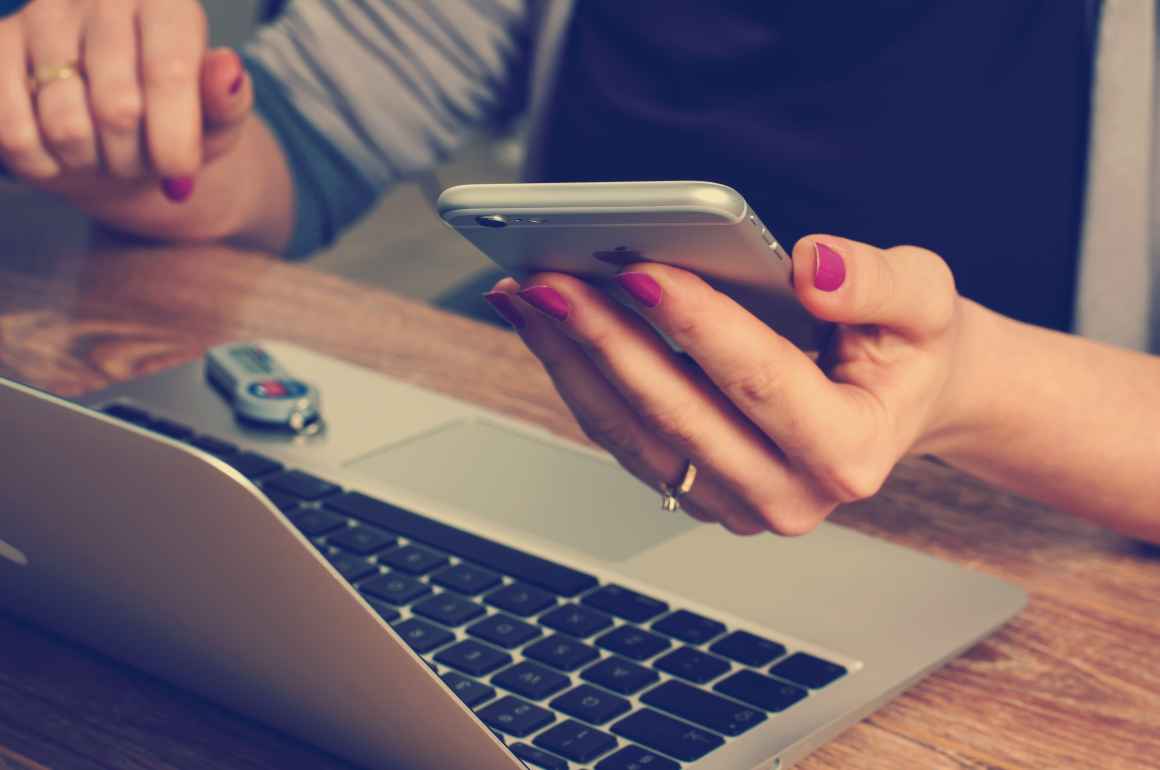 women holding cell phone, using computer & flash drive