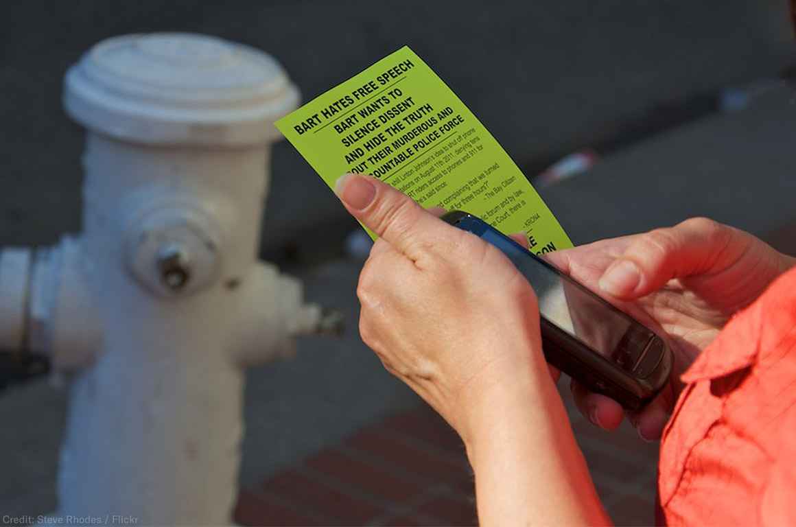 Person holding cell phone and flyer