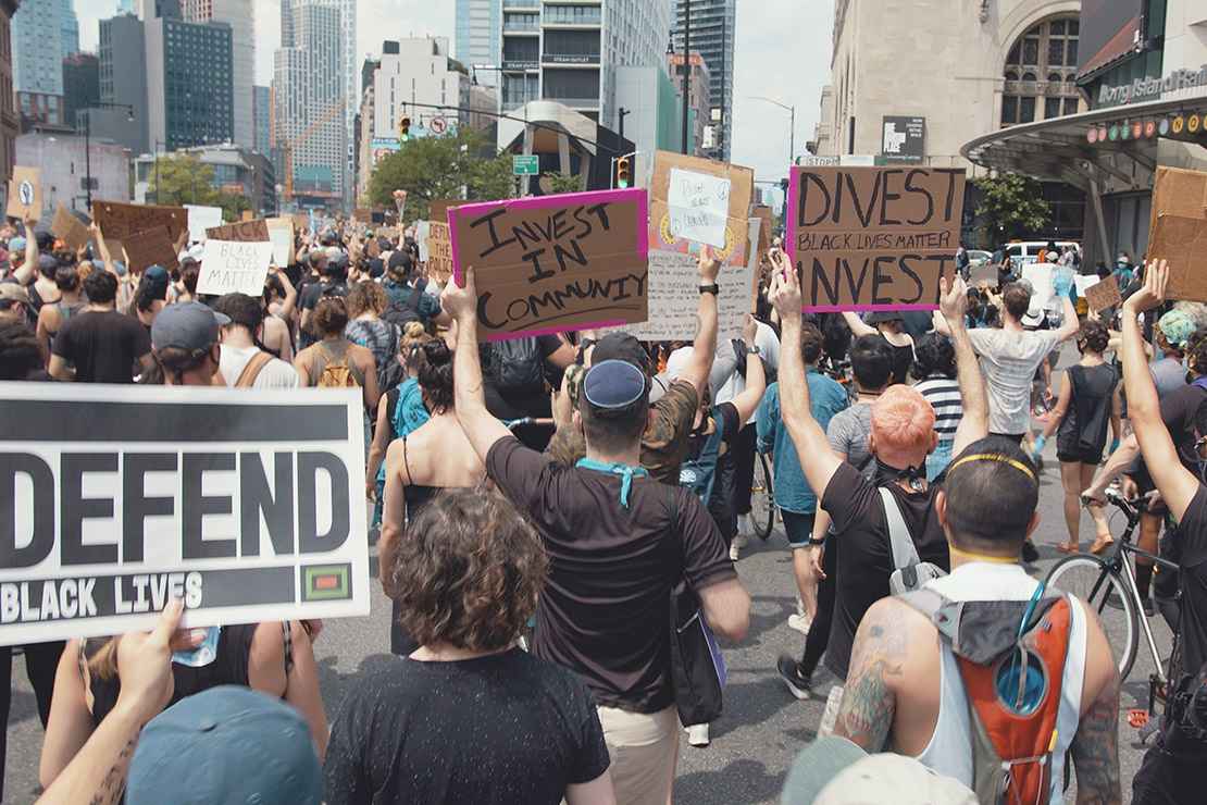 Protesters marching in a demonstration with signs calling on officials to divest from police and invest in communities.