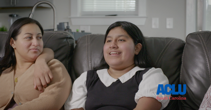 Skyler, a 13-year-old boy, smiles while talking. He is seated on a brown leather couch beside his mother.