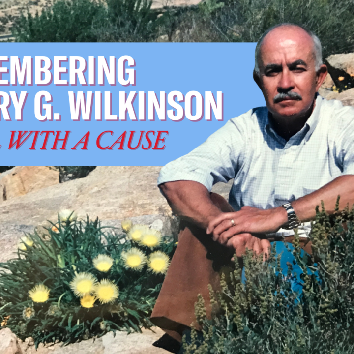 "Remembering Harry G. Wilkinson, Rebel with a Cause." Photo of Harry, a man in a button-up shirt with the sleeves rolled up, seated on some rocks with an outcropping of flowering scrub plants.