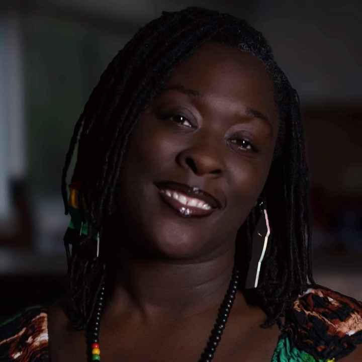 A photo of Brittany Martin. She is wearing a green, red, yellow, and black top and is smiling at the camera.