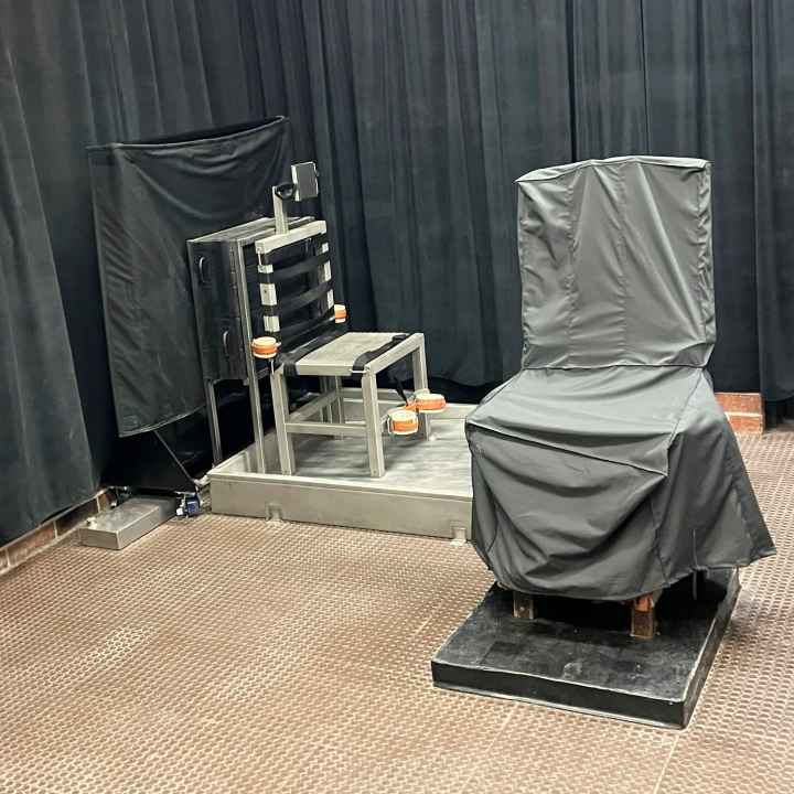 South Carolina's death chamber. A chair in the front is covered in gray cloth. Another chair is metal and has straps attached. The walls are covered by black curtains.