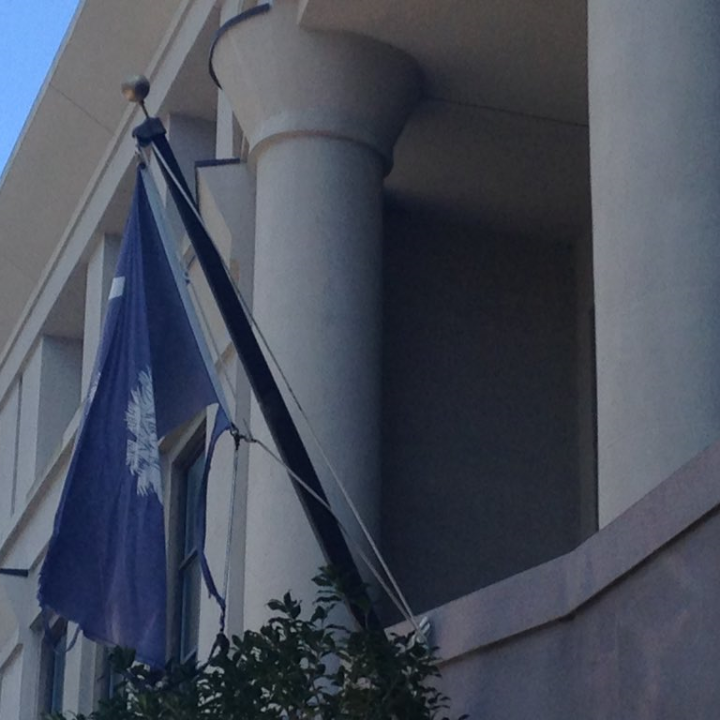 A tattered South Carolina flag hangs from a flagpole in front of the Charleston County School District office